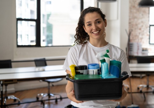 A member of the team from Pro Kleen Solutions, Office Cleaners in Pekin IL, holds a tub of cleaning products and smiles at the camera