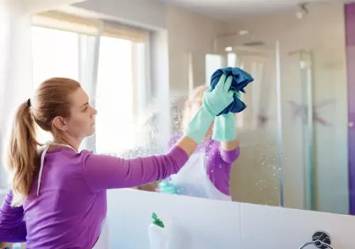 Female cleaning mirror during vacant residential cleaning in Pekin IL.