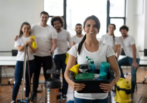 A group of team members from Pro Kleen, Office Cleaners in Peoria IL, smile while holding their cleaning supplies