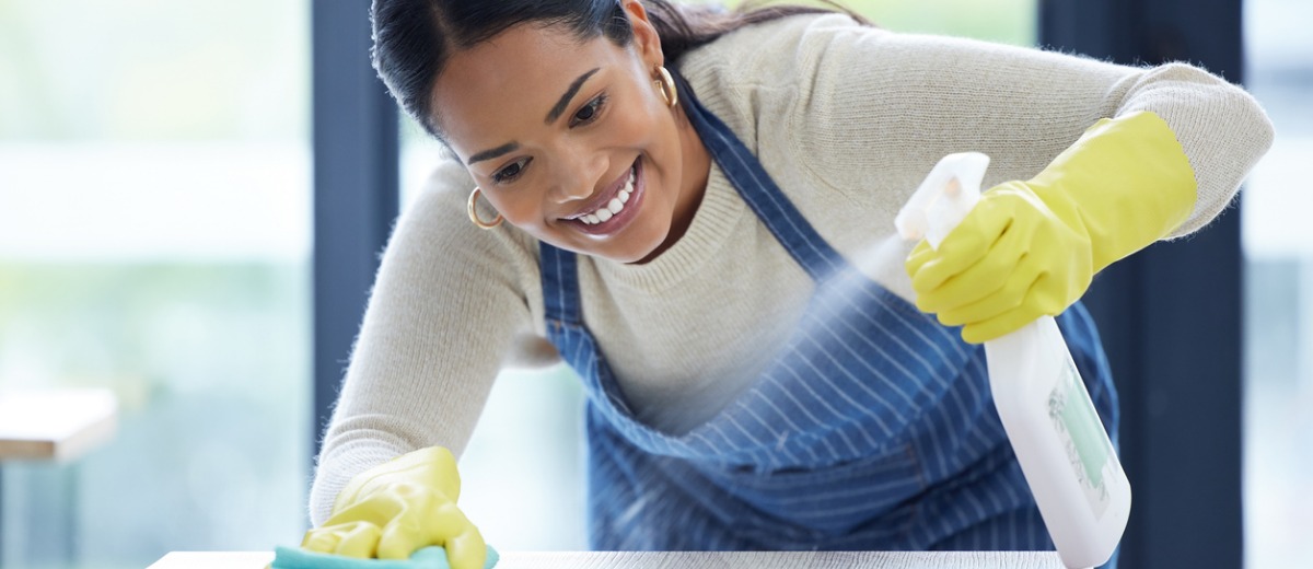 A woman smiles and sprays a desk while wiping it down as part of the work she does for Pro Kleen, a commercial cleaning company in Central Illinois