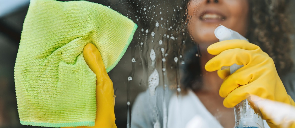 A woman working for Pro Kleen, which provides Champaign commercial cleaning services, sprays a window before wiping it down