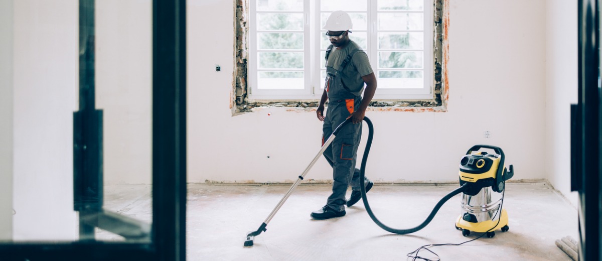 A member of Pro Kleen, a post-construction cleanup team, vacuums the floor of an unfinished apartment
