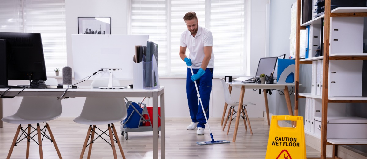 A member of the Pro Kleen team, which provides Peoria Commercial Cleaning Services, sweeps the floor of an office