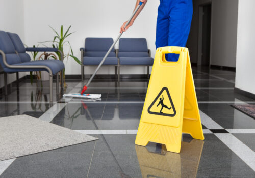 Office Cleaning Company Peoria IL, Close-up Of Man Cleaning The Floor With Yellow Wet Floor Sign